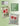 Two cross-stitched pillows with red berries and hearts on a light green background, featuring the Heart in Hand Needleworks logo.