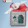 Cross-stitched snowman and house design on a box with a red ribbon, featuring 'Heart in Hand' branding.