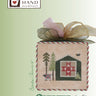 Cross-stitched design of a cabin with a barn quilt and sheep on a box, featuring the Heart in Hand Needleart logo.